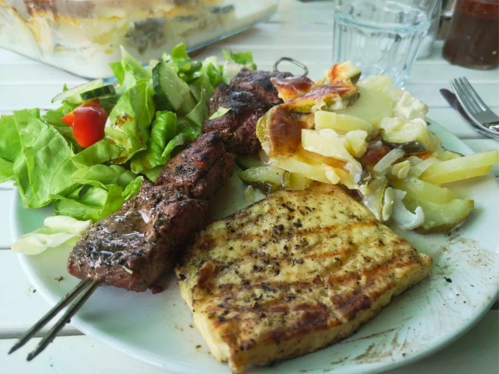 Teller mit gegrilltem Fleischspieß, Grillkäse, Kartoffelgratin und grünem Salat