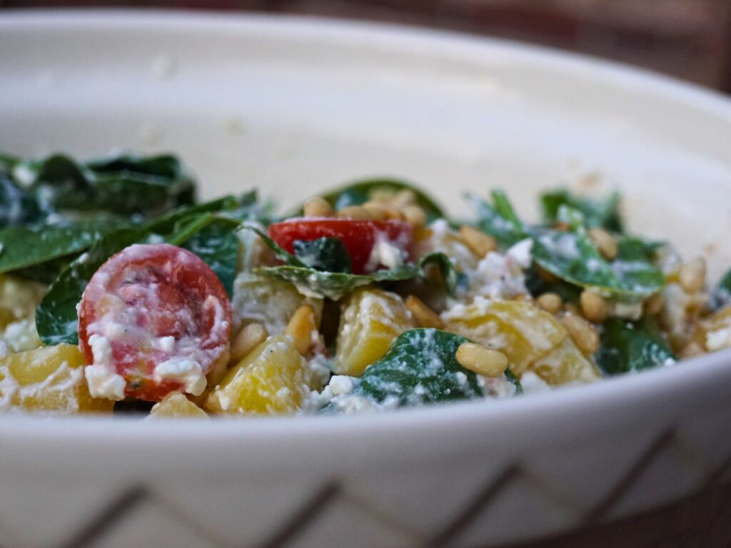 Kartoffelsalat mit Salat, Tomaten und gerösteten Pinienkernen. Leicht mit Hüttenkäse