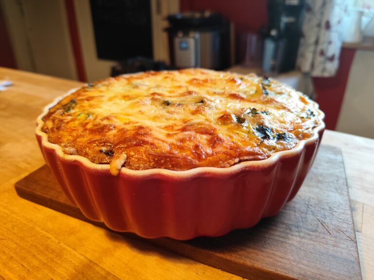 quiche mit Mangold oder Spinat auf einem Holzbrett